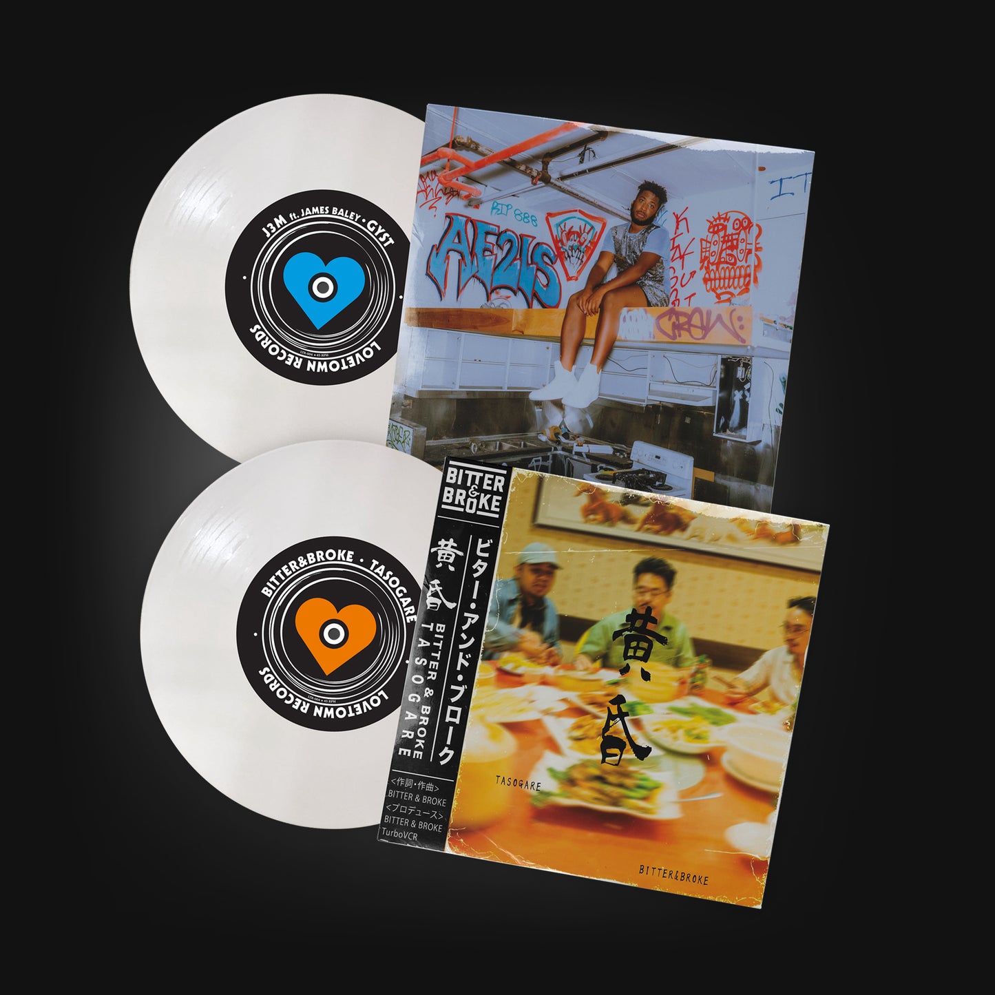 Showing both sides of a seven inch white vinyl record. One side has a blue heart on the centre label with the name J3M ft. James Baley - GYST and LOVETOWN RECORDS printed on it. The cover is a photo of a black guy sitting on a shelf in an industrial kitchen covered in graffiti. The other side has a label with an orange heart and the names Bitter&Broke Tasogare printed on it. This side's cover is an obscure photo of three pan-asian men sitting in a restaurant with a table full of food.