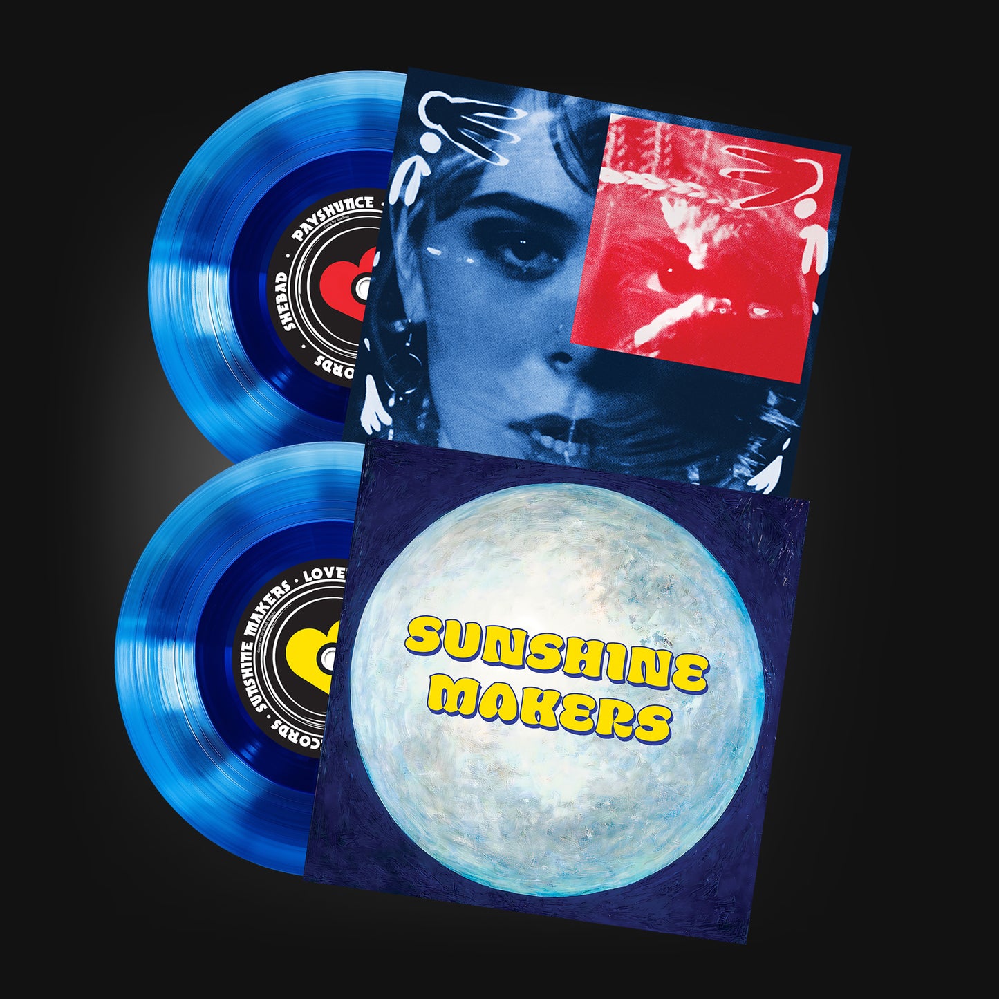 Showing two sides of a seven inch vinyl record that is a translucent blue. The cover for each side has a woman's face on one and a painting of the moon with the name sunshine makers on over it. The records have a coloured heart on the centre label.